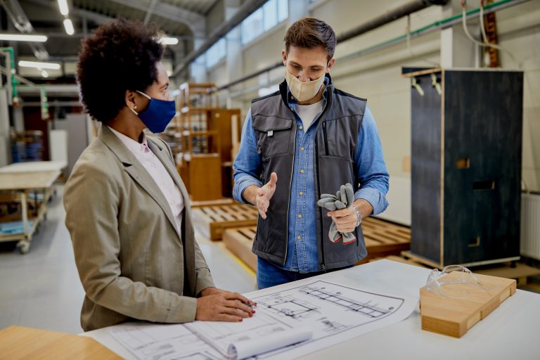Male carpenter explaining design plans to African American femal